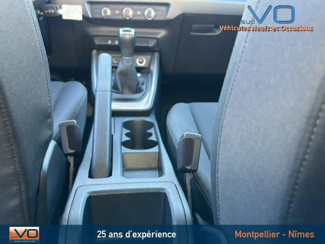 Vue intérieure centrée sur la console centrale et levier de vitesses manuelle de l'Audi A1 Sportback gris foncé.