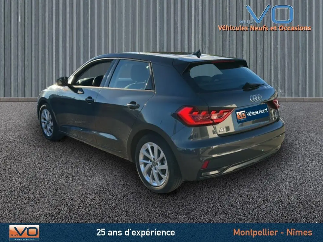 Audi A1 Sportback gris foncé vue 3/4 arrière côté gauche, avec jantes 16 pouces et feux arrière allumés.