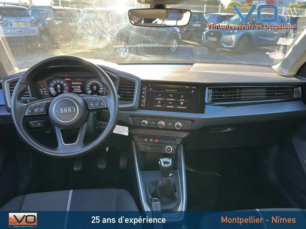 Vue intérieure de face de l'Audi A1 Sportback gris foncé, volant cuir, tableau de bord avec écran tactile et boîte manuelle.