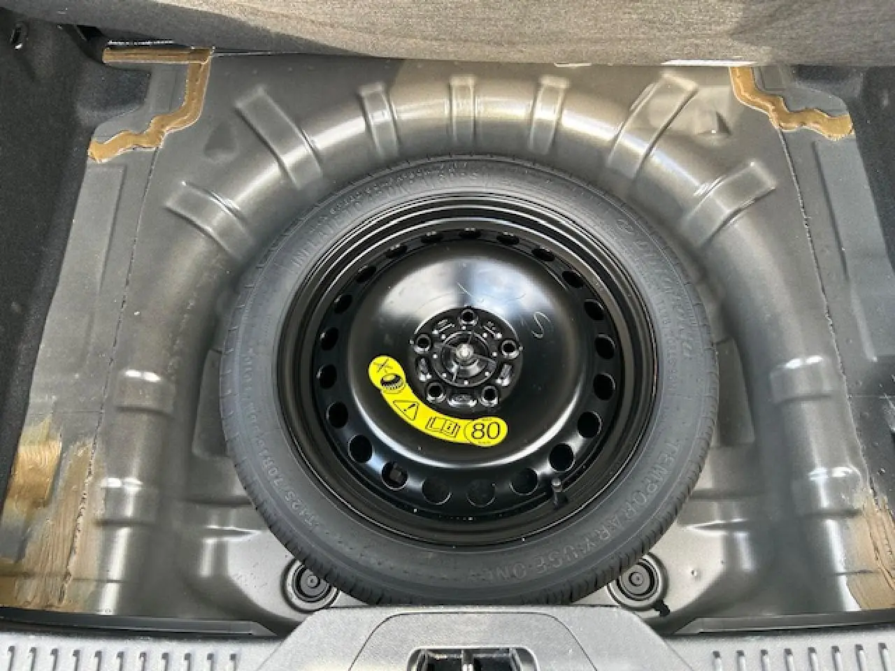 Vue plongeante sur la roue de secours galette noire dans le coffre de la Ford Focus IV gris Magnetic Metal.