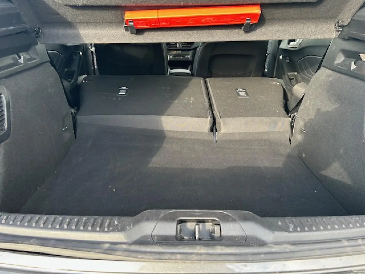 Coffre ouvert vu de l'arrière avec banquette arrière rabattue, intérieur noir d'une Ford Focus IV gris Magnetic Metal.