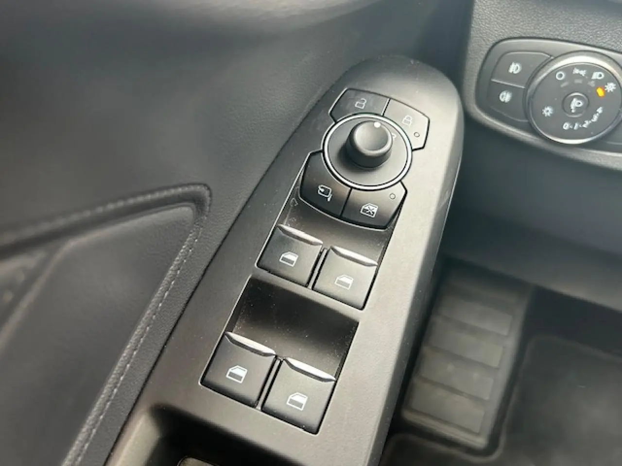 Gros plan sur les commandes des vitres et rétroviseurs côté gauche de la Ford Focus IV ST-Line X gris Magnetic Metal.