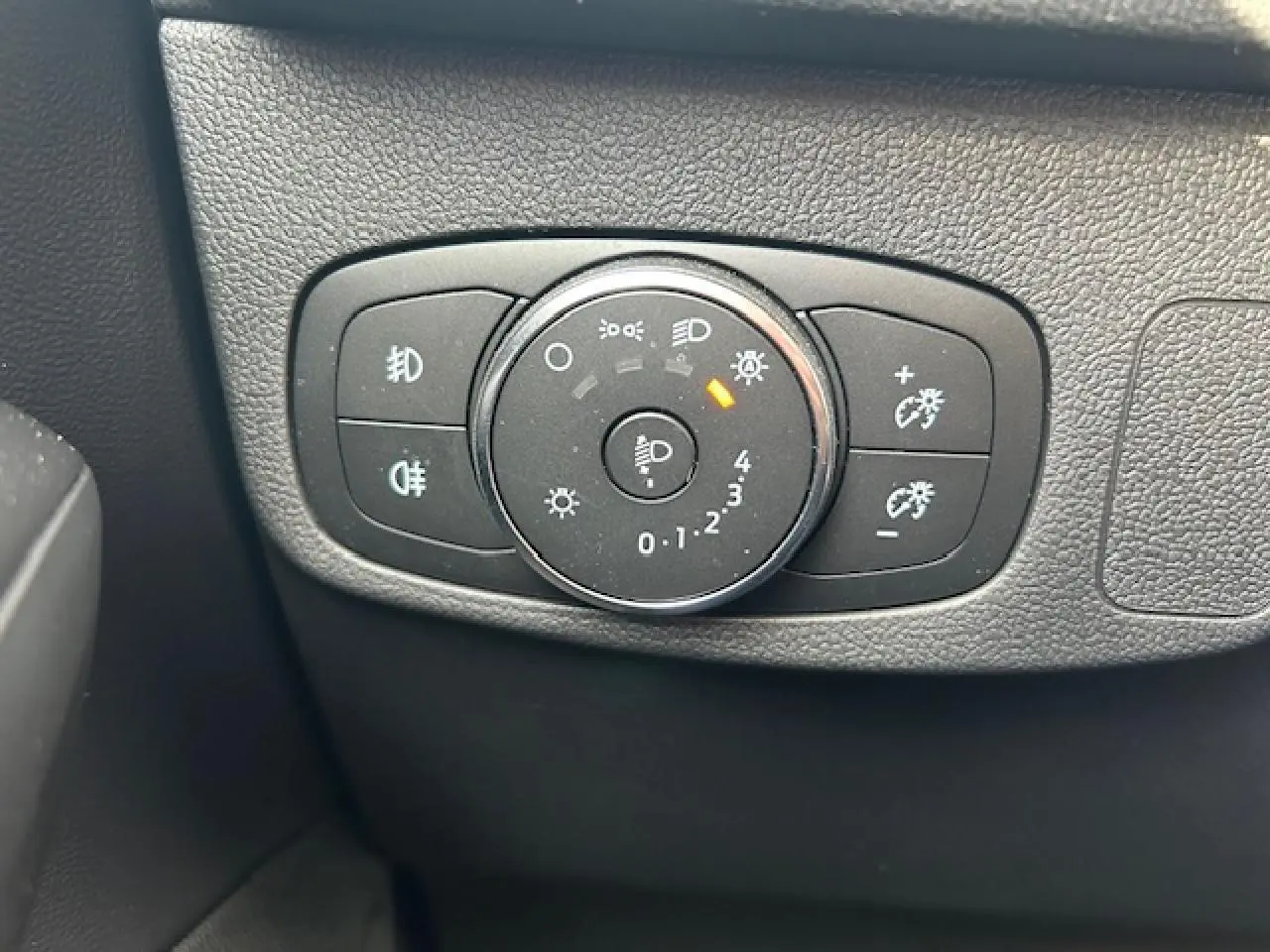 Gros plan sur le bouton de réglage des phares et feux antibrouillard dans l’habitacle d’une Ford Focus gris magnetic.