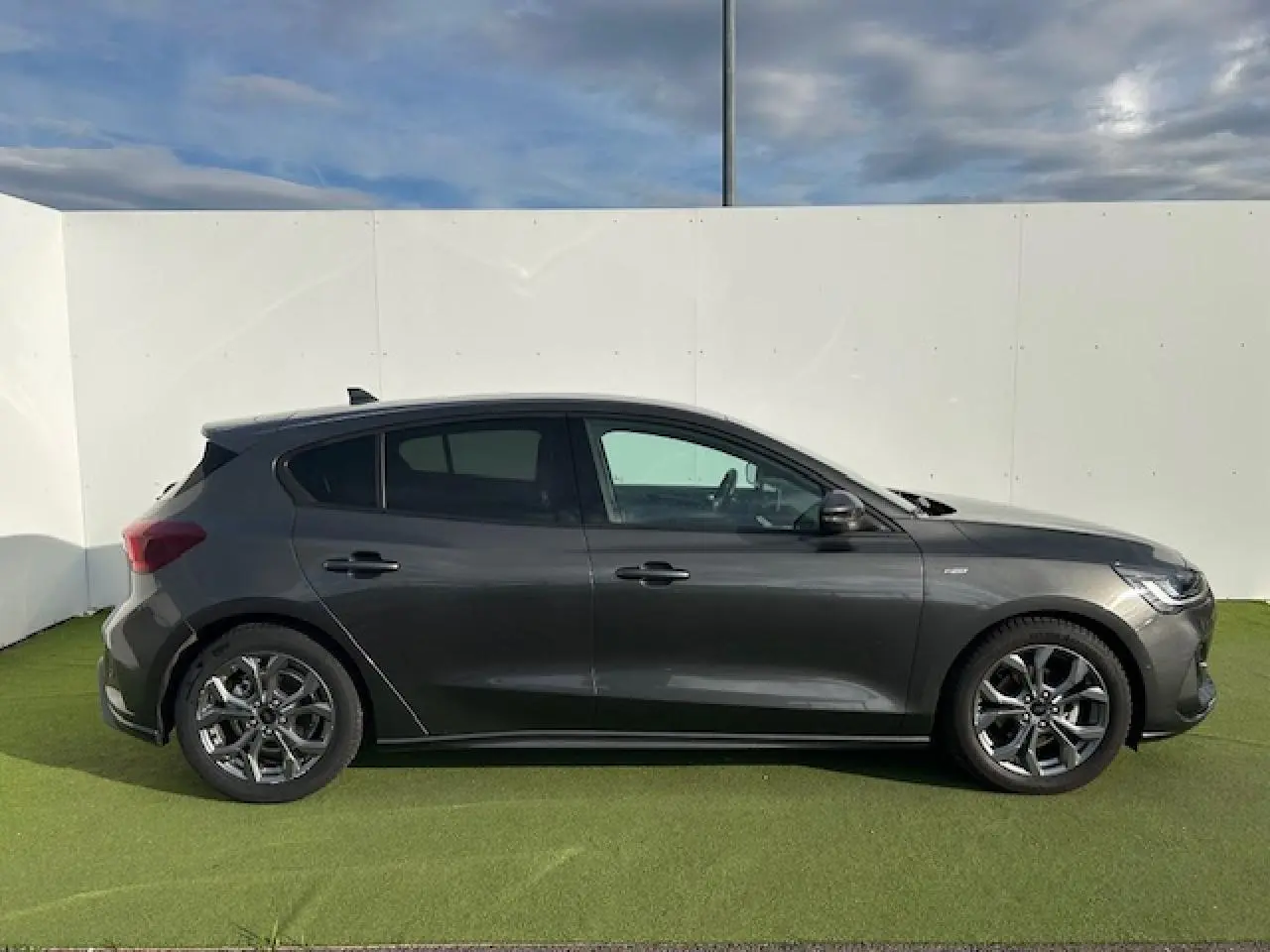 Ford Focus IV ST-Line X gris métallique vue de profil côté gauche sur fond clair avec jantes alliage 17 pouces.