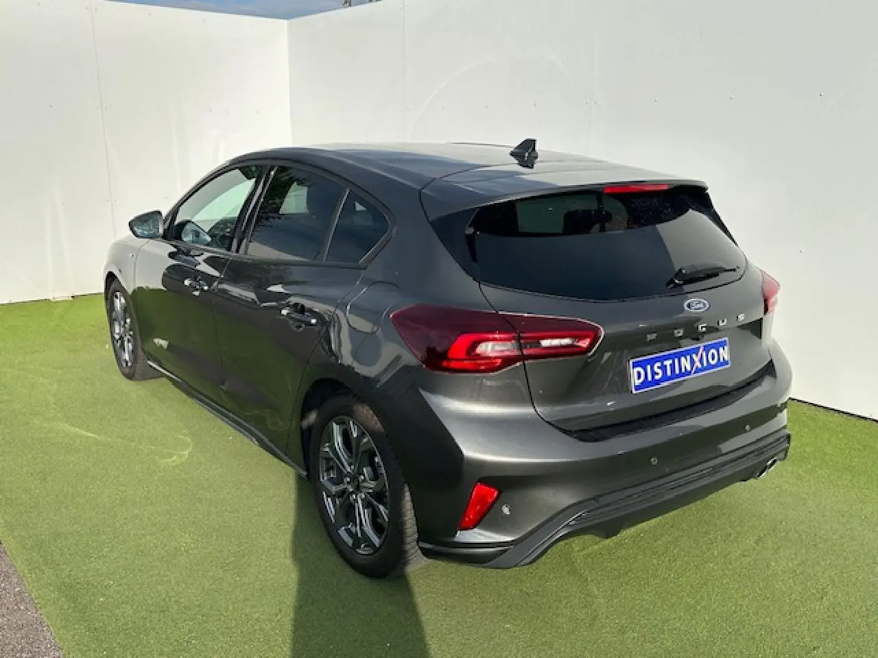 Vue 3/4 arrière droite d'une Ford Focus IV ST-Line X gris magnetic métallisé avec jantes alliage et double sortie d'échappement.