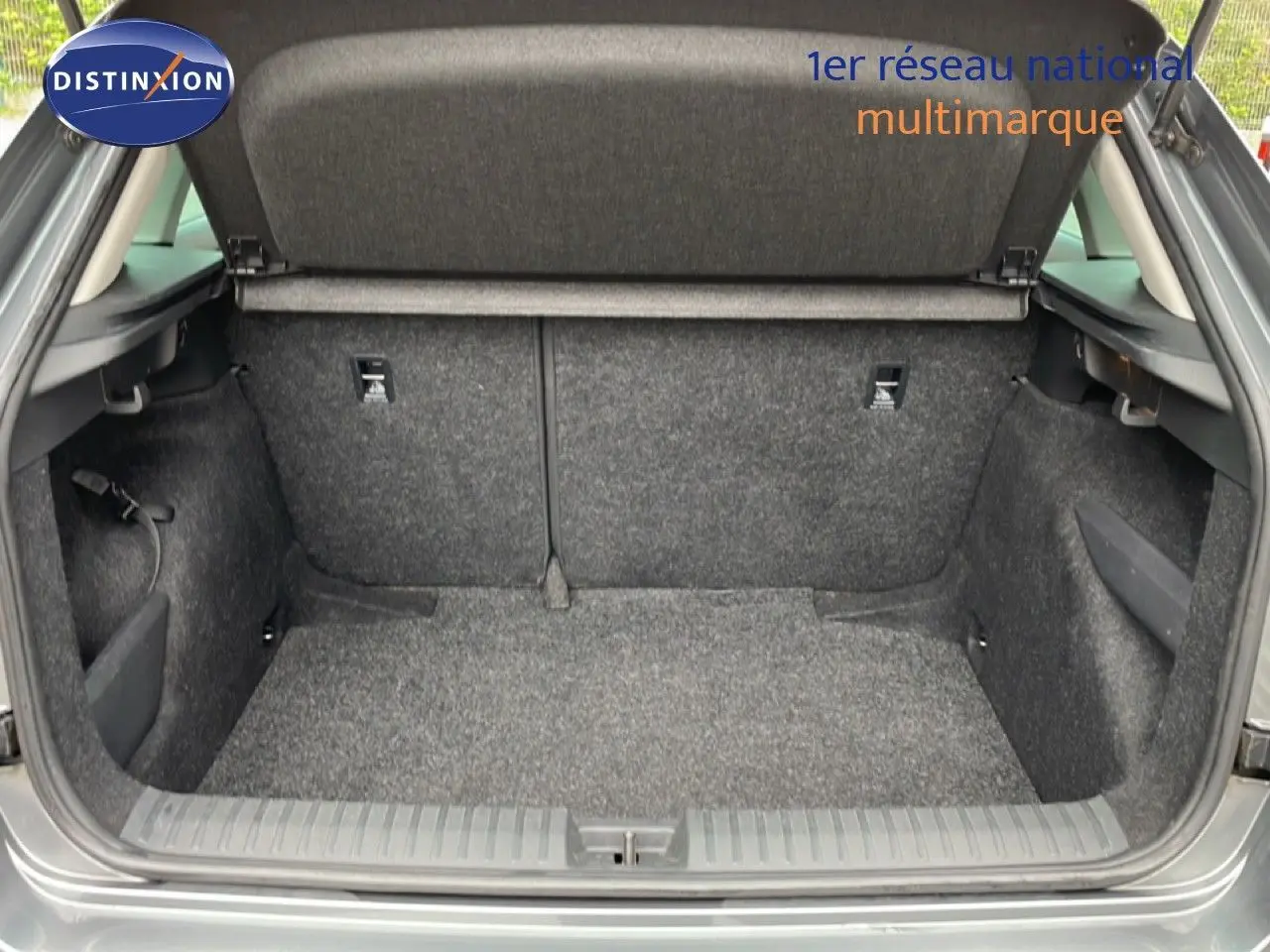 Coffre ouvert d’un Skoda Kamiq gris graphite métal, vue arrière montrant l’espace de chargement vide et revêtement tissu gris.
