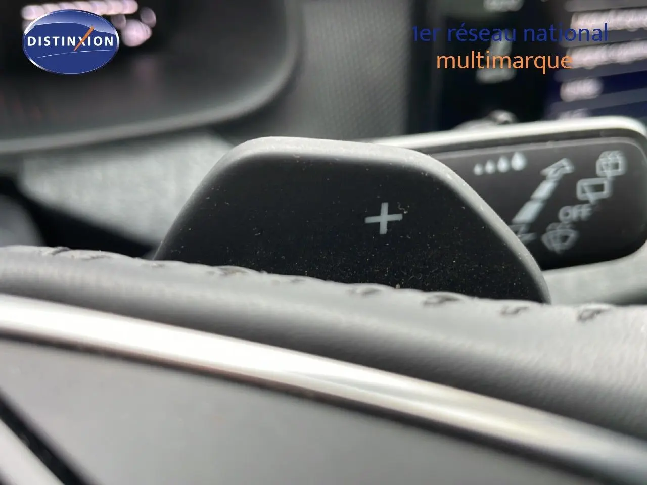 Détail du levier de commande + au volant cuir du Skoda Kamiq gris graphite, avec commandes d’essuie-glace en arrière-plan flou.