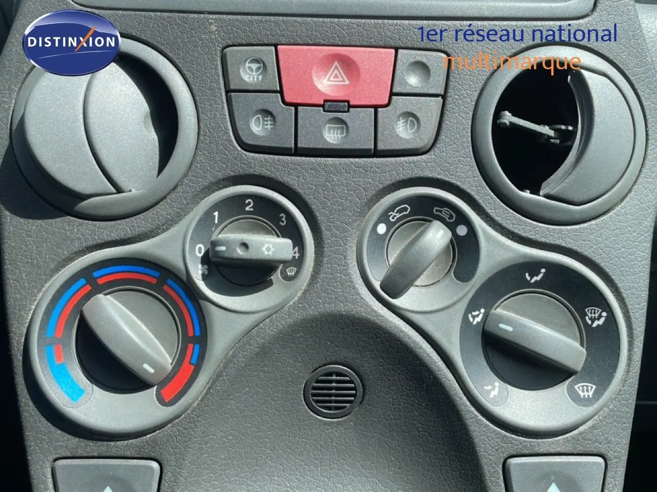 Gros plan sur les commandes de climatisation et ventilation du tableau de bord d'une Fiat Panda blanche de 2011.