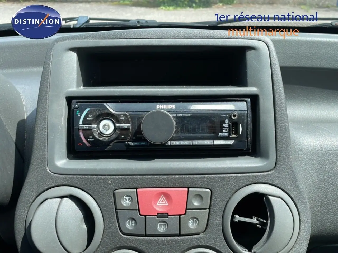 Gros plan sur la console centrale de la Fiat Panda blanche 2011, mettant en valeur l'autoradio Philips et les commandes de ventilation.