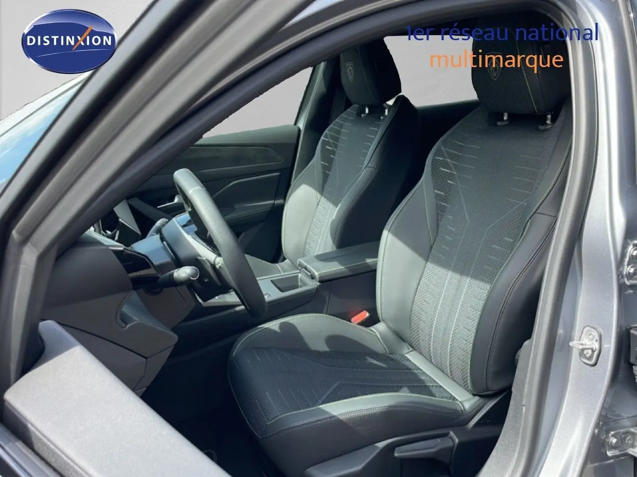 Vue intérieure côté conducteur de la Peugeot 308 gris Artense, sièges tissu et cuir noir avec volant multifonction.
