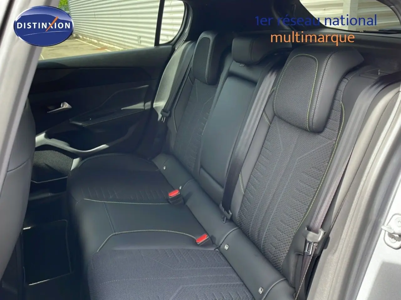 Vue intérieure sur la banquette arrière de la Peugeot 308 gris Artense, avec sièges en tissu et cuir noir, ceintures visibles.