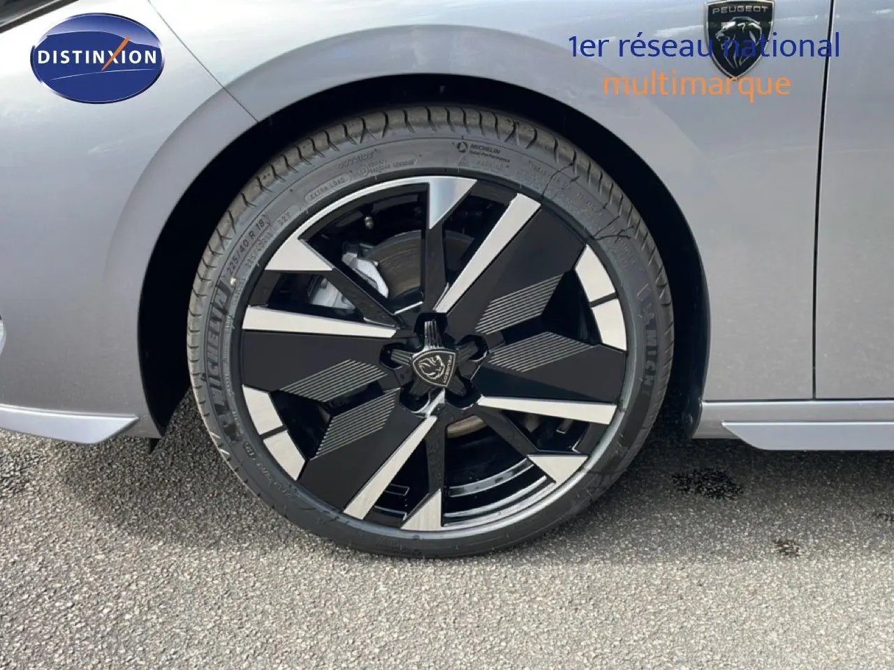 Gros plan sur la roue avant droite d’une Peugeot 308 gris Artense métal avec jante noire et argentée au design géométrique.