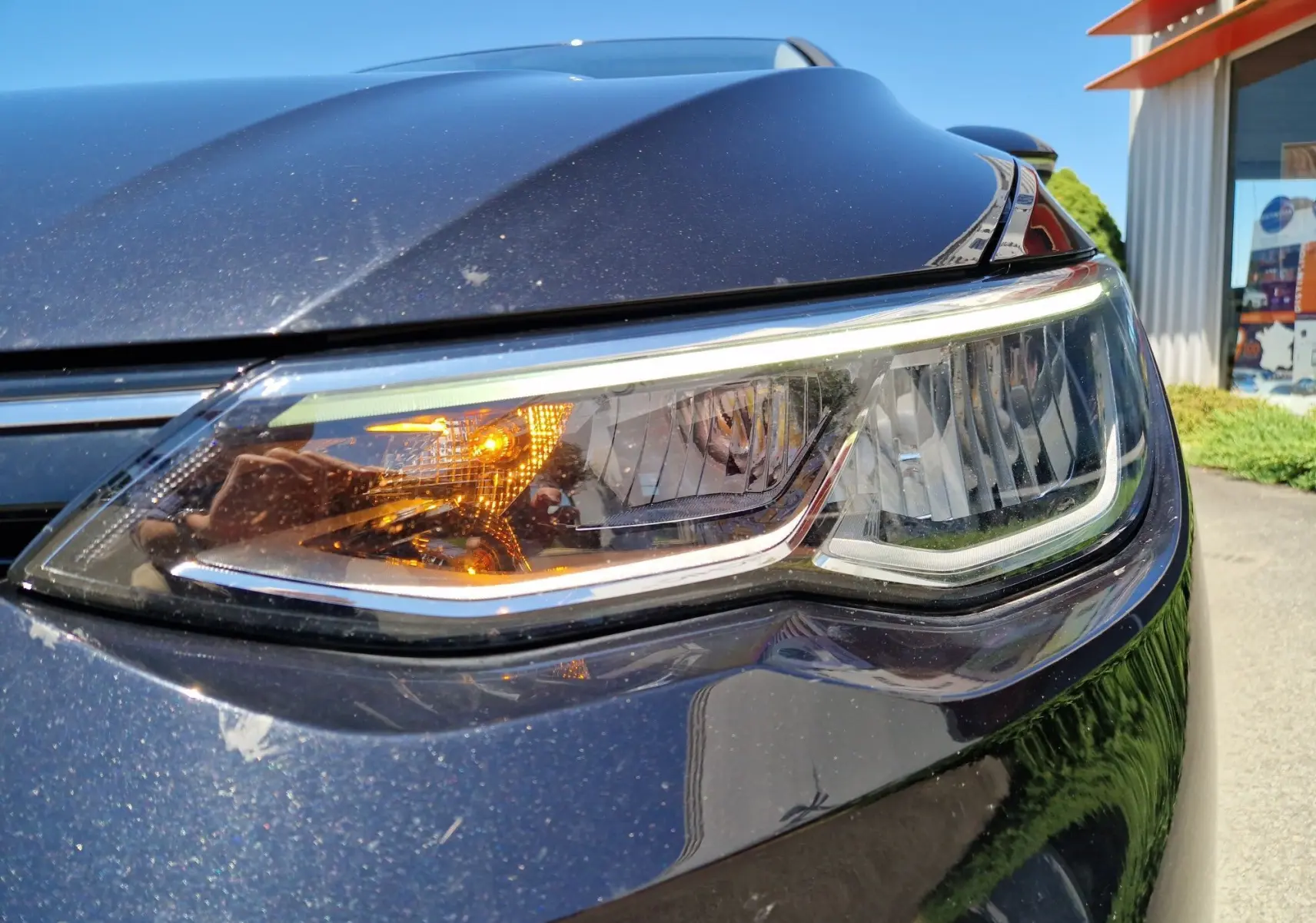 Gros plan sur le phare avant droit d'une Volkswagen Golf VIII noire métal, avec clignotant allumé.