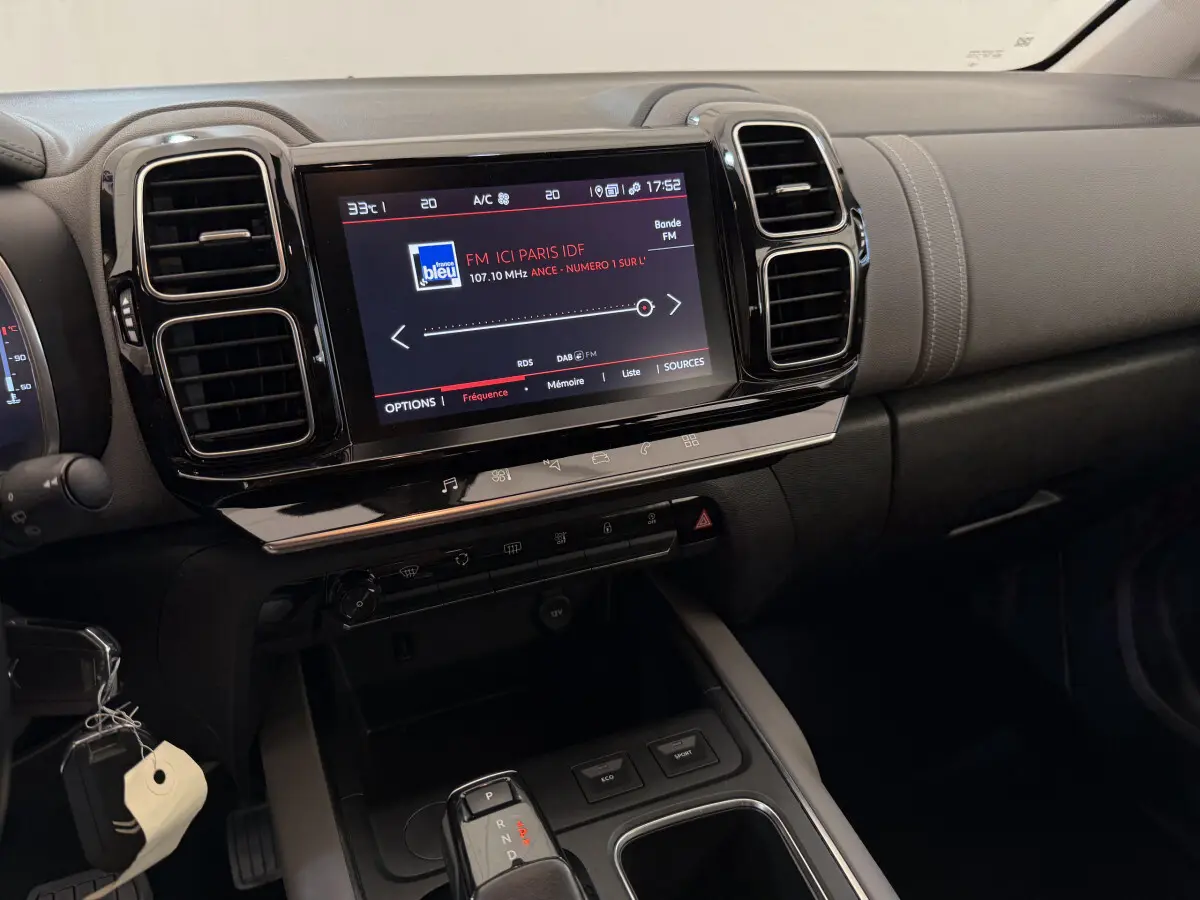 Vue rapprochée du tableau de bord noir du Citroën C5 Aircross avec écran tactile affichant une radio FM.