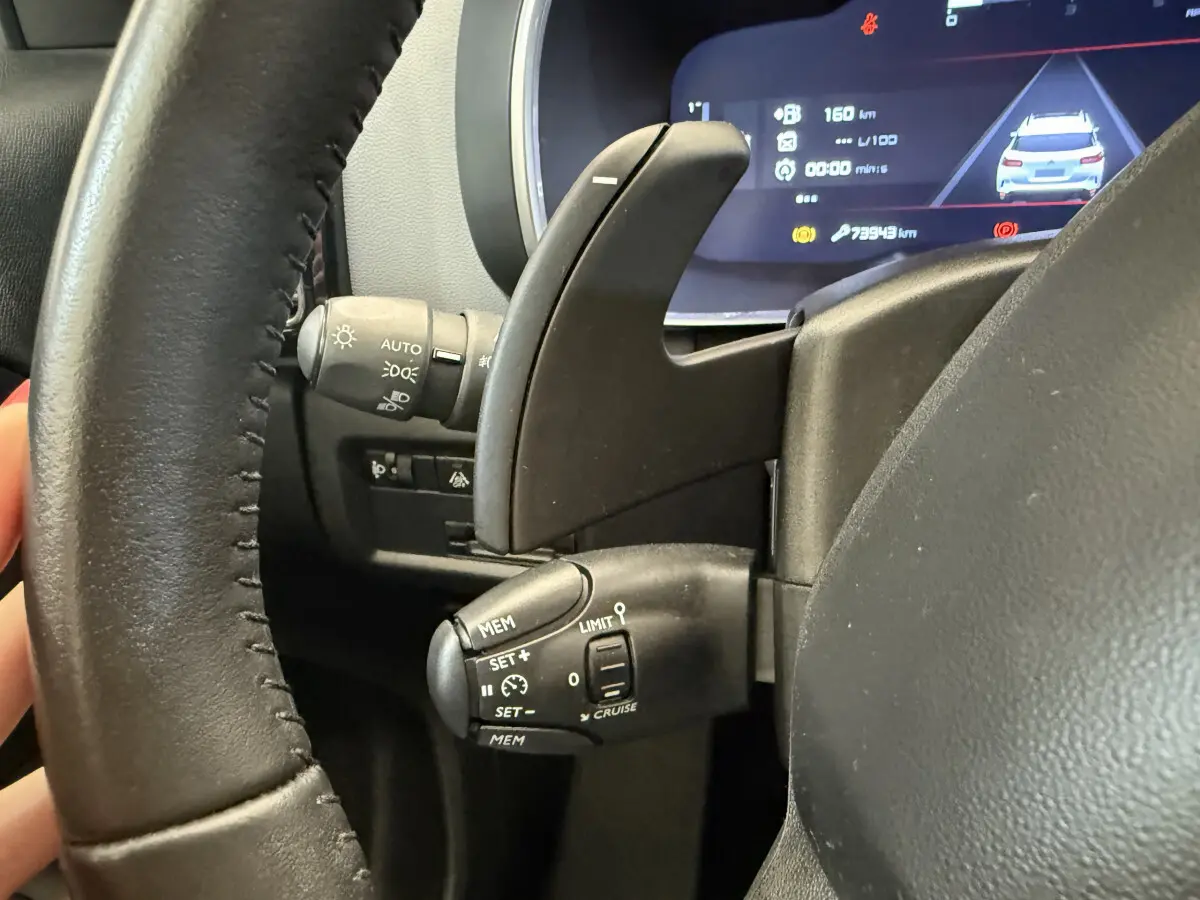 Gros plan sur le volant cuir noir de la Citroën C5 Aircross 2020, avec commandes de régulateur et affichage numérique.