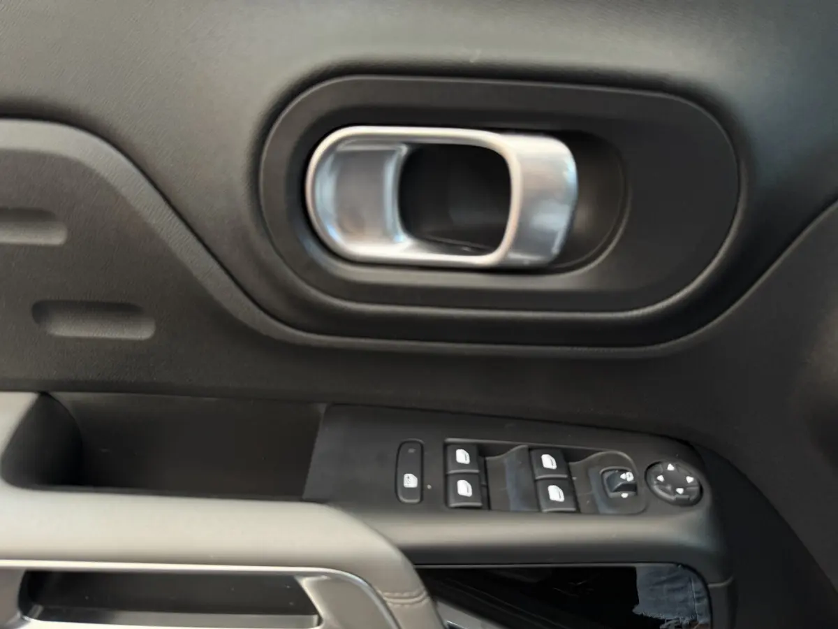Poignée intérieure et commandes des vitres côté conducteur d'un Citroën C5 Aircross gris clair, vue rapprochée.