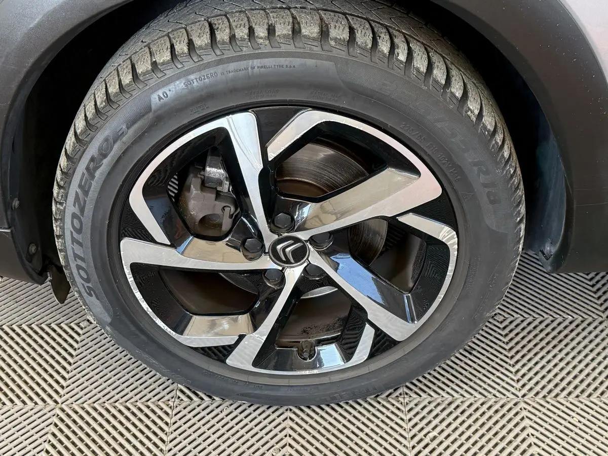 Gros plan sur la roue avant droite du Citroën C5 Aircross gris clair, avec jante alliage bicolore et logo Citroën central.