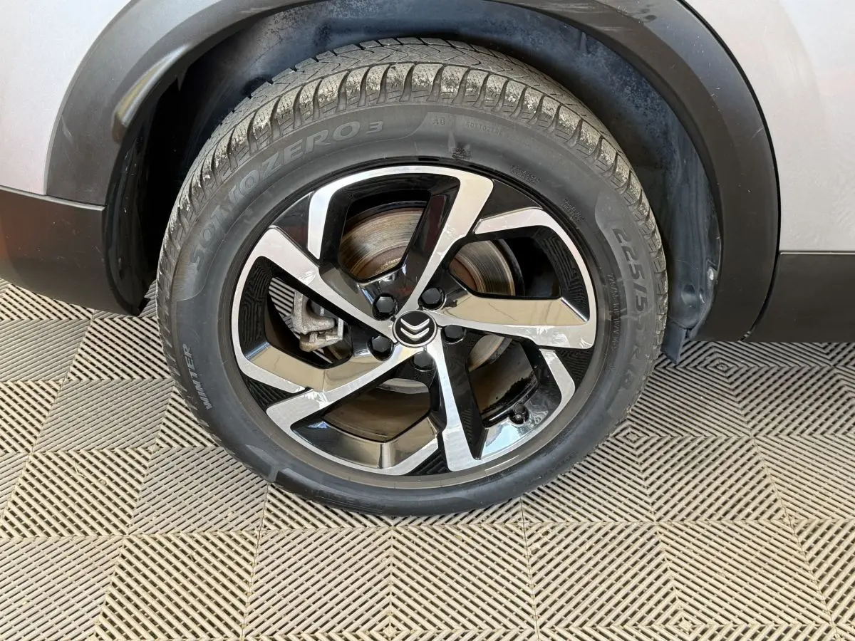 Gros plan sur la roue avant gauche gris clair du Citroën C5 Aircross avec jante alliage noire et argentée au design moderne.