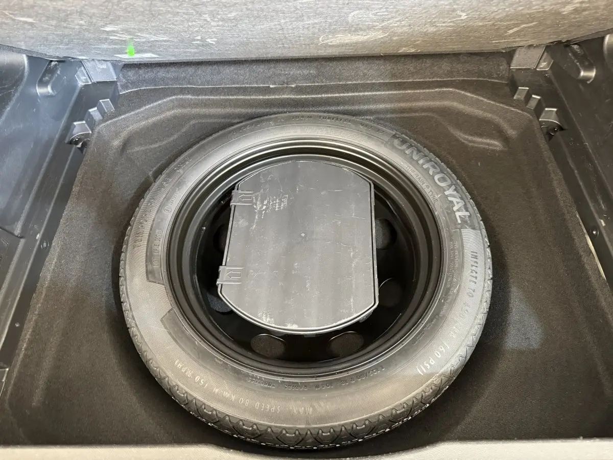 Vue plongeante sur la roue de secours Uniroyal dans le coffre d'un Citroën C5 Aircross gris clair 2020.