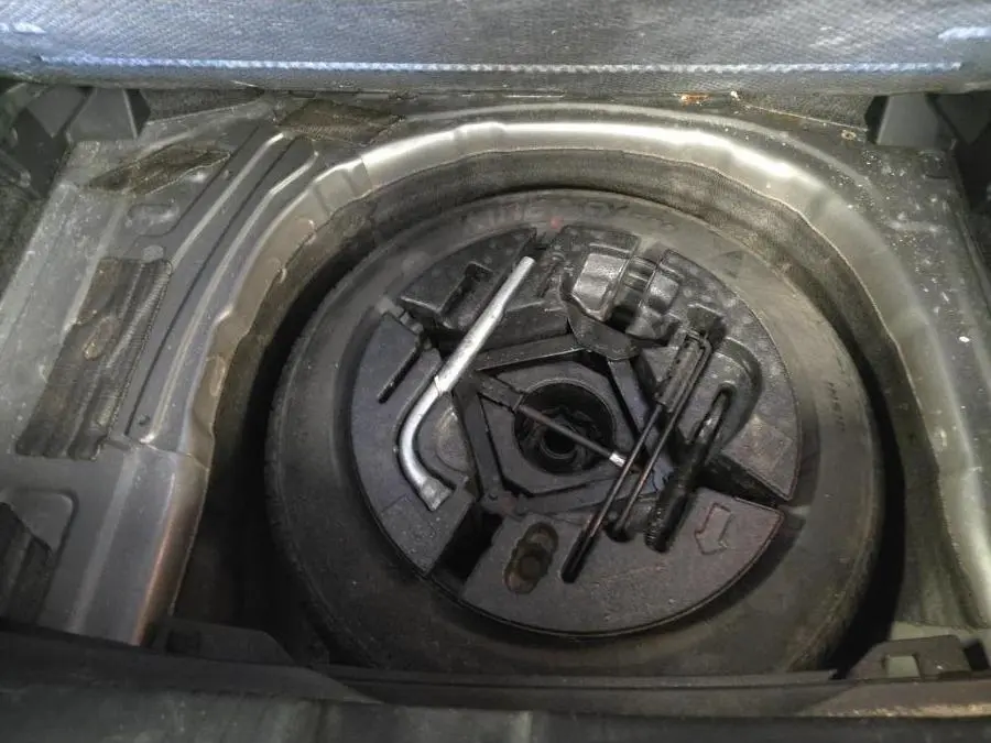Vue en plongée sur la roue de secours et les outils de bord du coffre d'une Volkswagen Polo gris Urano 2020.