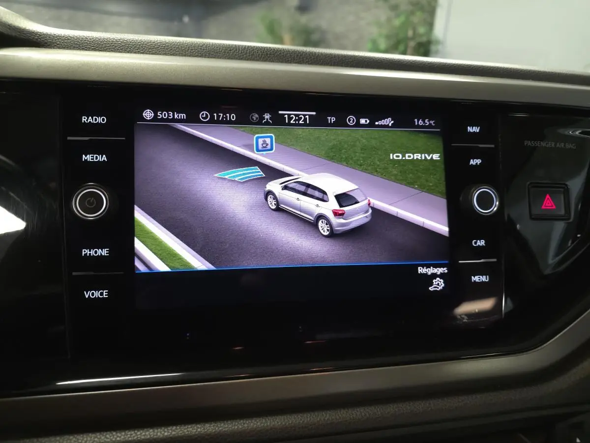 Écran de navigation affichant une voiture grise vue en 3/4 arrière sur une route virtuelle