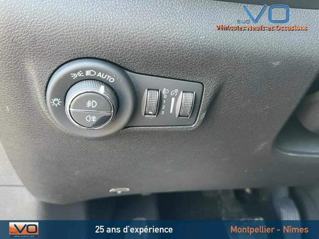 Gros plan sur le tableau de bord du Jeep Compass 2024 noir, montrant la molette des feux automatiques et réglages d’éclairage.