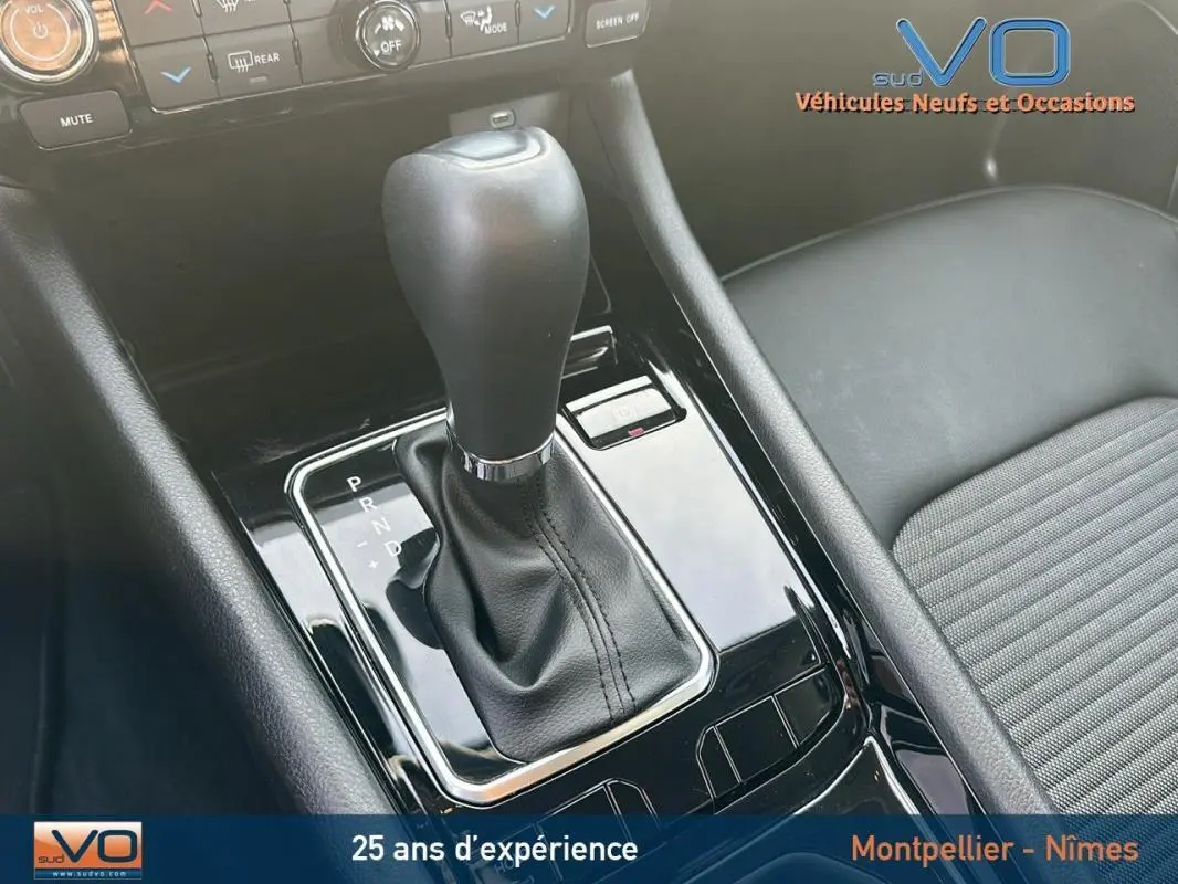 Gros plan sur la console centrale noire du Jeep Compass 2024, mettant en valeur le levier de vitesse automatique et l'accoudoir.