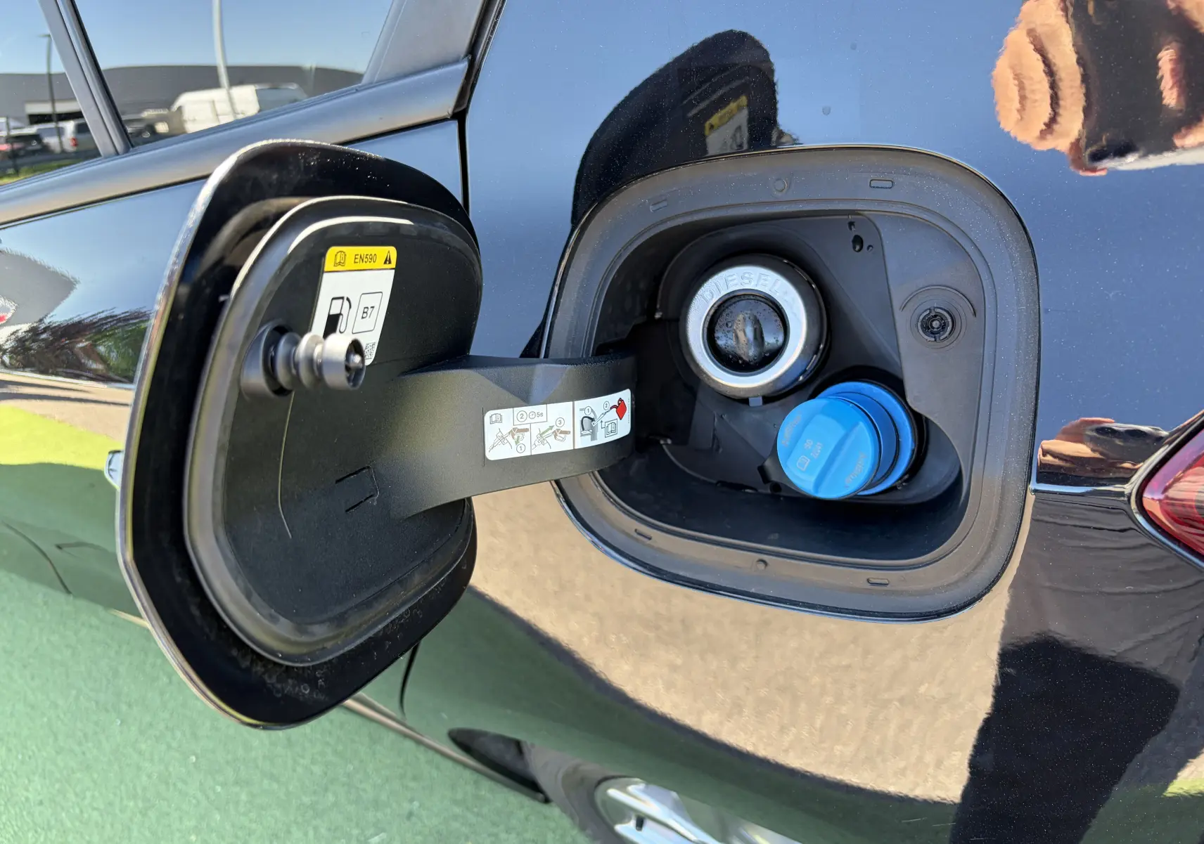 Vue rapprochée de la trappe à carburant ouverte côté gauche sur Ford Focus IV noire Agate avec bouchon diesel et AdBlue.