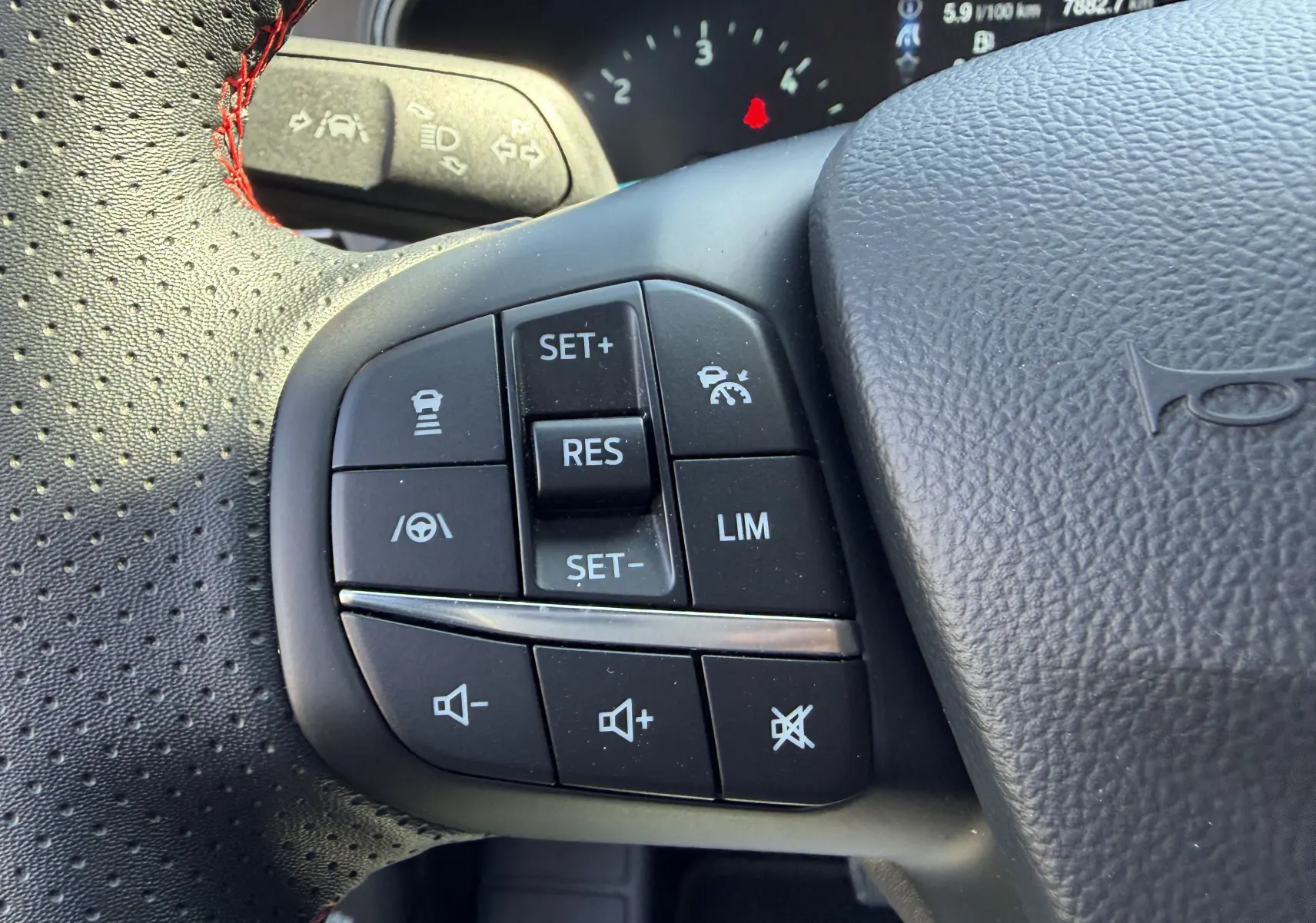 Gros plan sur les commandes gauche du volant noir perforé avec surpiqûres rouges de la Ford Focus IV ST-Line X 2025.