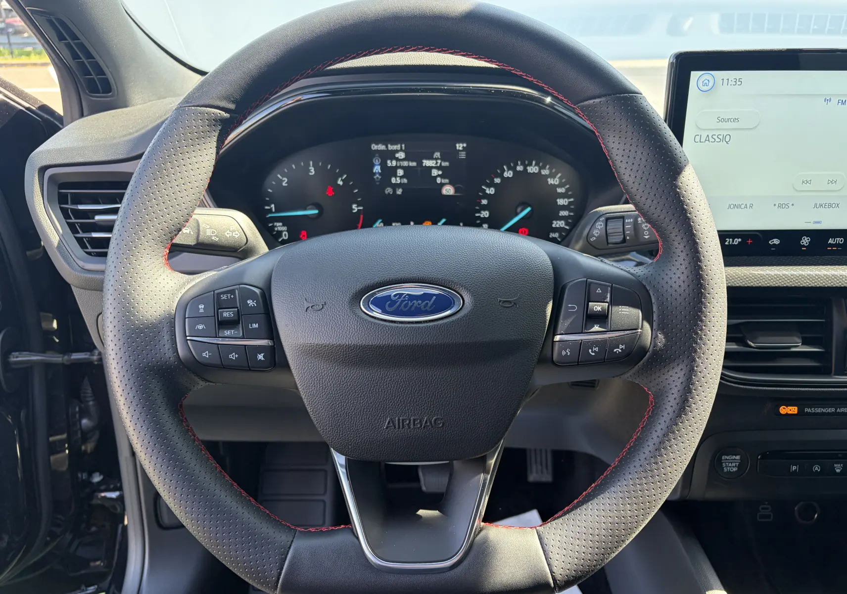 Vue intérieure centrée sur le volant noir perforé avec surpiqûres rouges de la Ford Focus IV ST-Line X 2025.