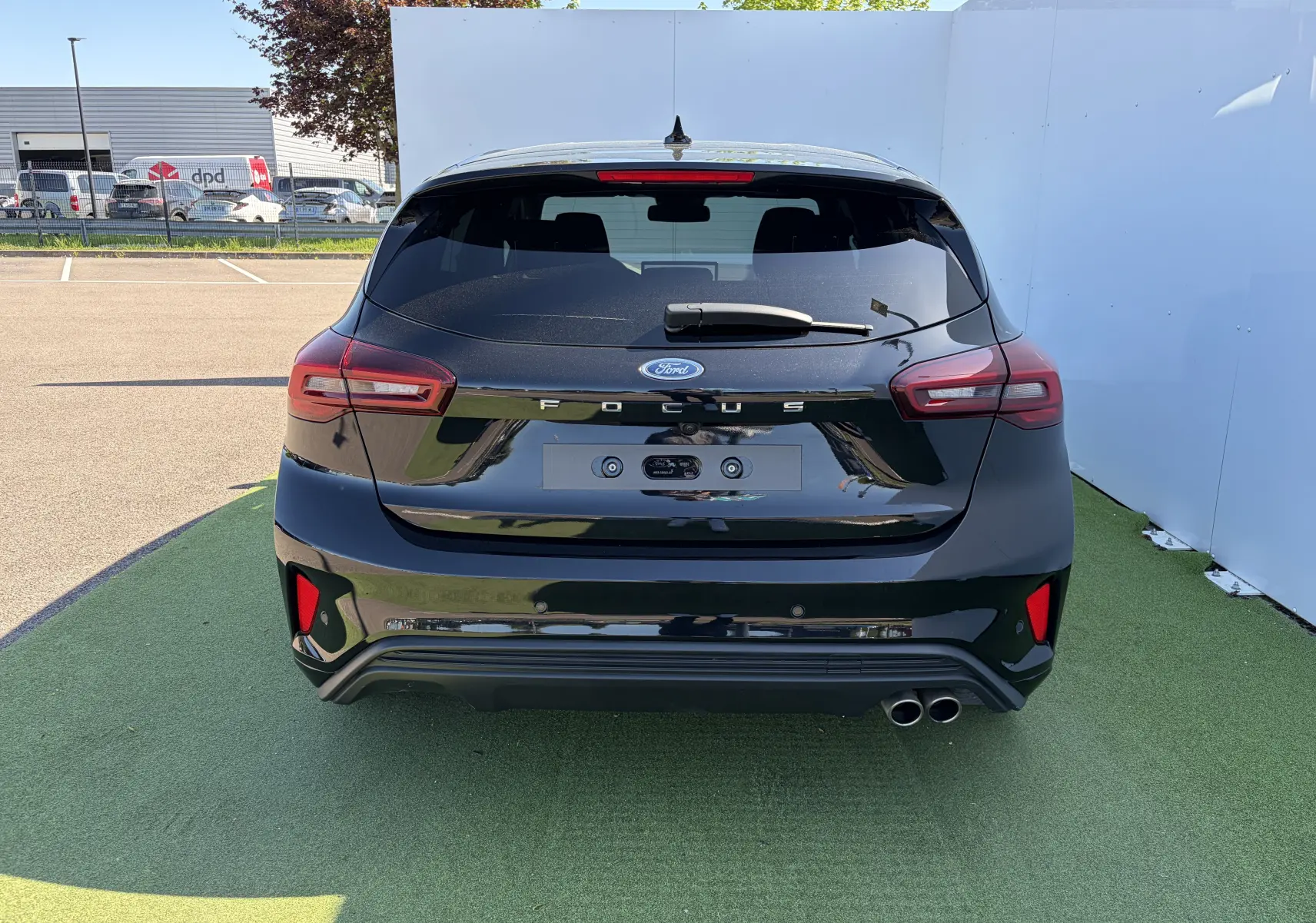 Vue arrière d'une Ford Focus IV noire Agate avec double sortie d'échappement et feux arrière LED distinctifs.