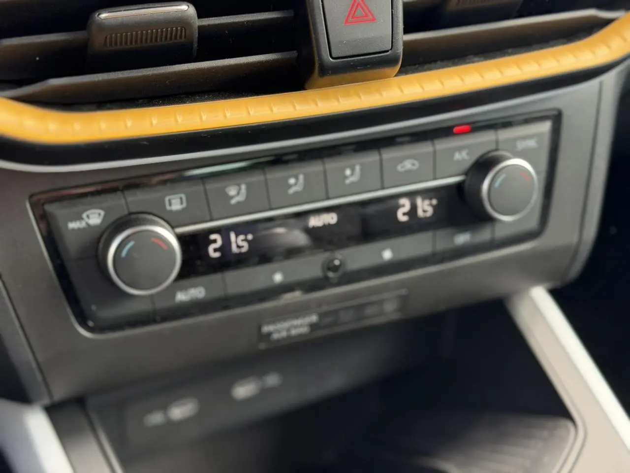 Gros plan sur la commande de climatisation automatique bi-zone du SEAT Arona, avec finition noire et insert jaune.
