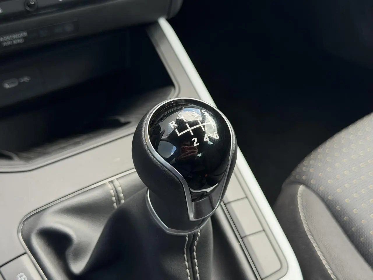 Gros plan sur le levier de vitesse manuel noir avec coutures blanches, intérieur tissu gris du SEAT Arona 2025.