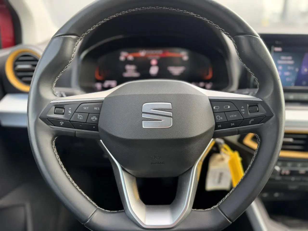 Vue rapprochée du volant noir de la SEAT Arona 2025 avec commandes intégrées et détails jaunes sur la planche de bord.