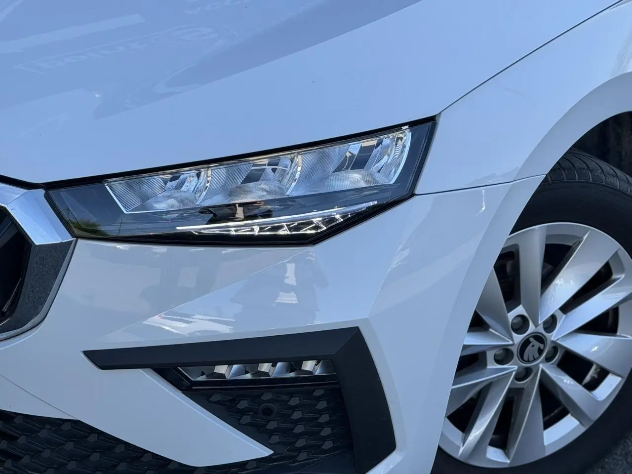 Gros plan sur l'avant droit blanc glacier d'une Skoda Scala TSI 116, mettant en valeur le phare LED et la jante alliage.