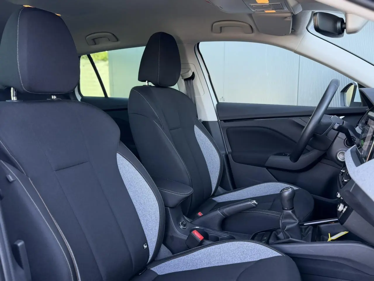 Vue intérieure côté droit de la Skoda Scala TSI 116 avec sièges bi-matière noirs et gris, volant multifonctions.