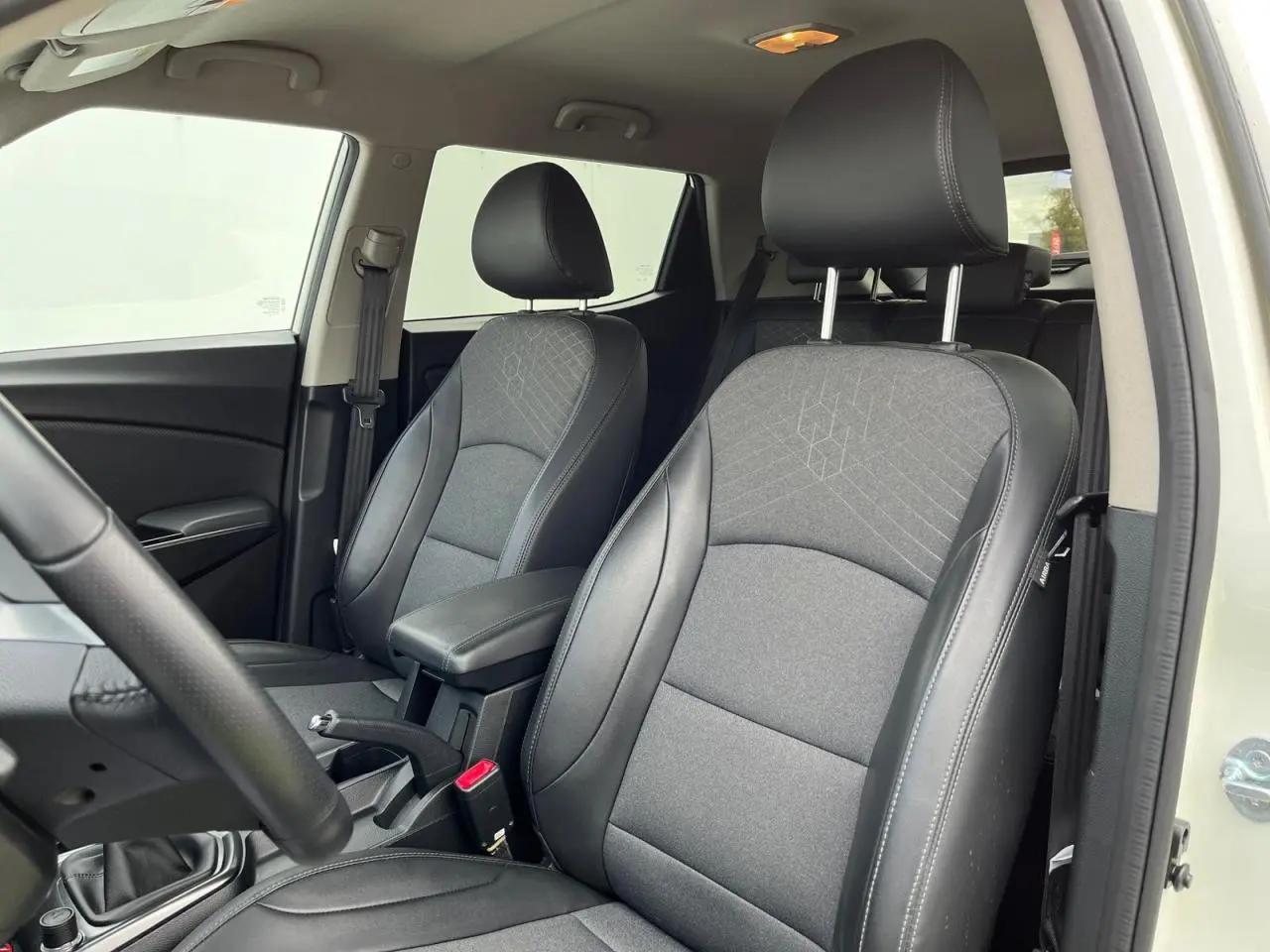 Vue intérieure côté conducteur du SSANGYONG TIVOLI 2021, sièges tissu et cuir noir avec surpiqûres grises.