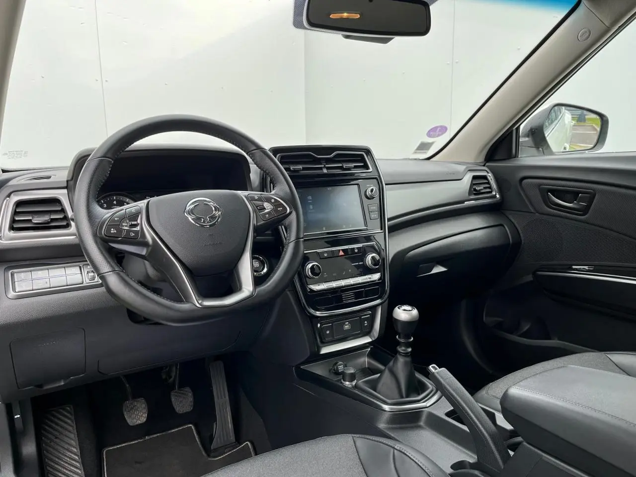 Intérieur du SsangYong Tivoli 2021 vu de face, volant cuir, écran tactile 8 pouces et boîte manuelle visible.