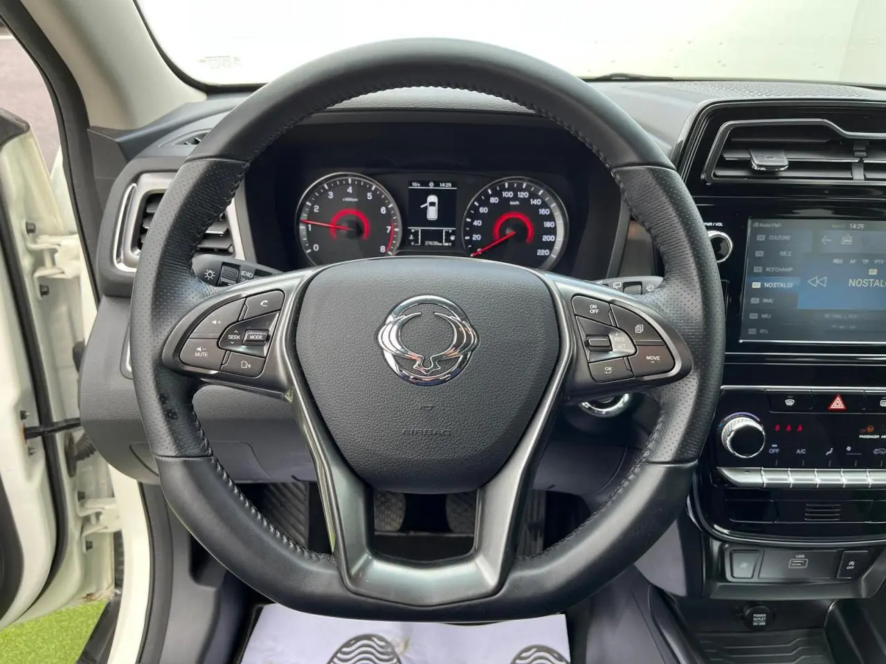 Vue intérieure centrée sur le volant cuir du SsangYong Tivoli blanc 2021 avec tableau de bord et écran tactile 8 pouces.