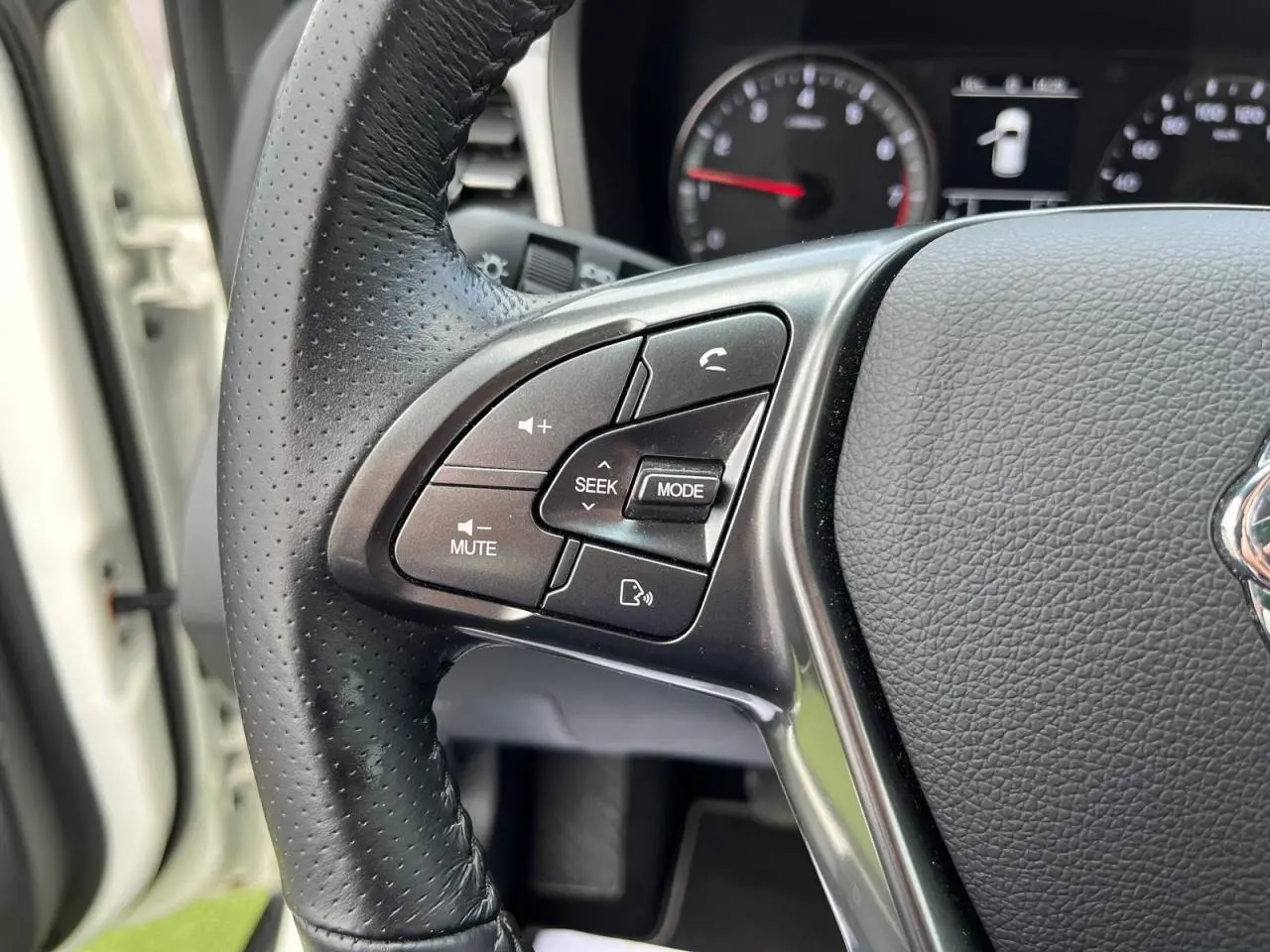 Gros plan sur les commandes audio et téléphone au volant cuir perforé du SSANGYONG TIVOLI blanc 2021.