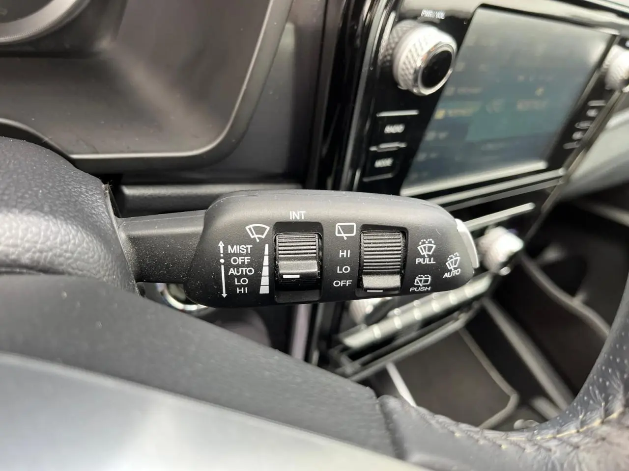 Gros plan sur la commande d’essuie-glace à gauche du volant dans l’habitacle noir du SsangYong Tivoli blanc 2021.