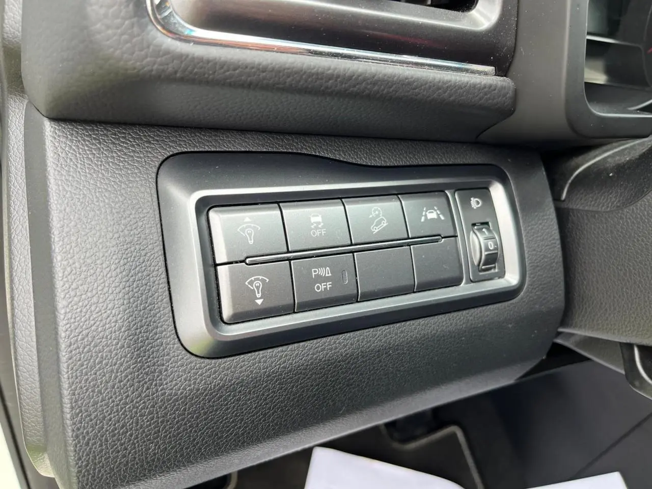 Gros plan sur les commandes d'assistance et réglage des phares côté gauche du tableau de bord du SsangYong Tivoli blanc 2021.