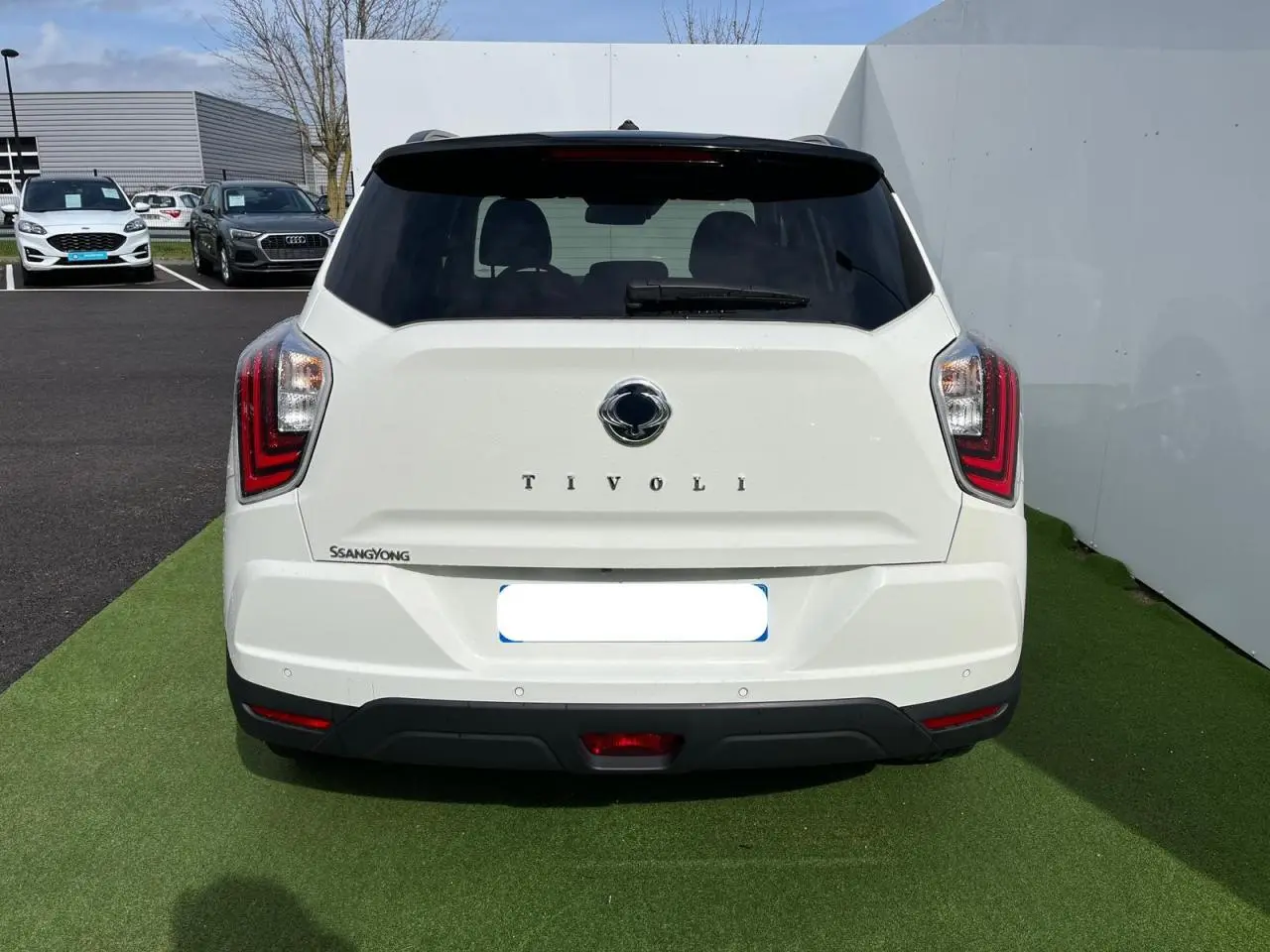 Vue arrière d'un SsangYong Tivoli blanc 2021 avec feux LED et vitre arrière surteintée sur fond extérieur.