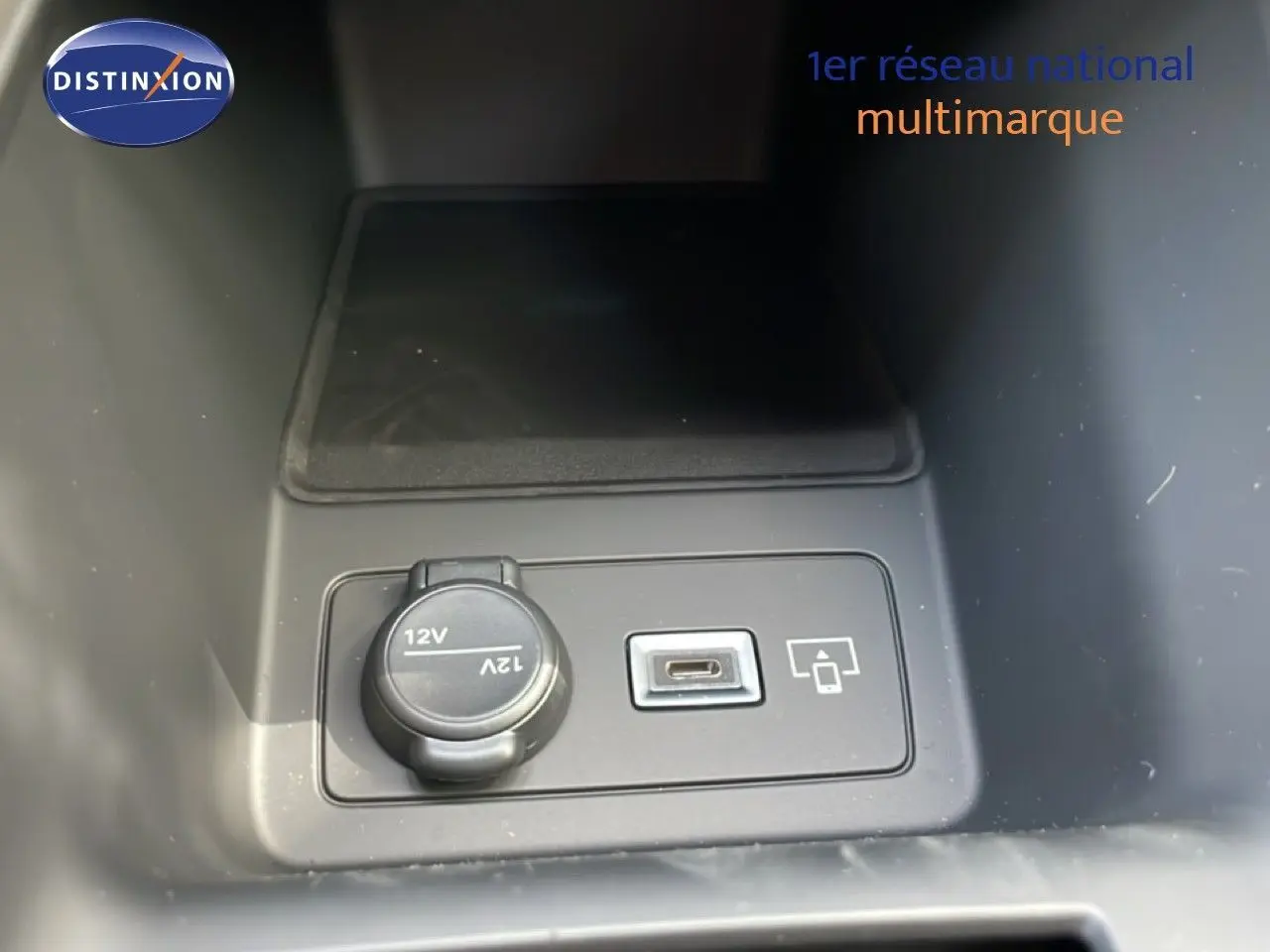 Prise 12V et port USB-C en gros plan dans l’espace de rangement central d’une Peugeot 308 gris Artense.