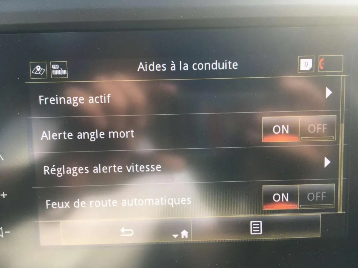 Écran tactile intérieur montrant les aides à la conduite activées sur Renault Kadjar gris titanium, vue frontale rapprochée.