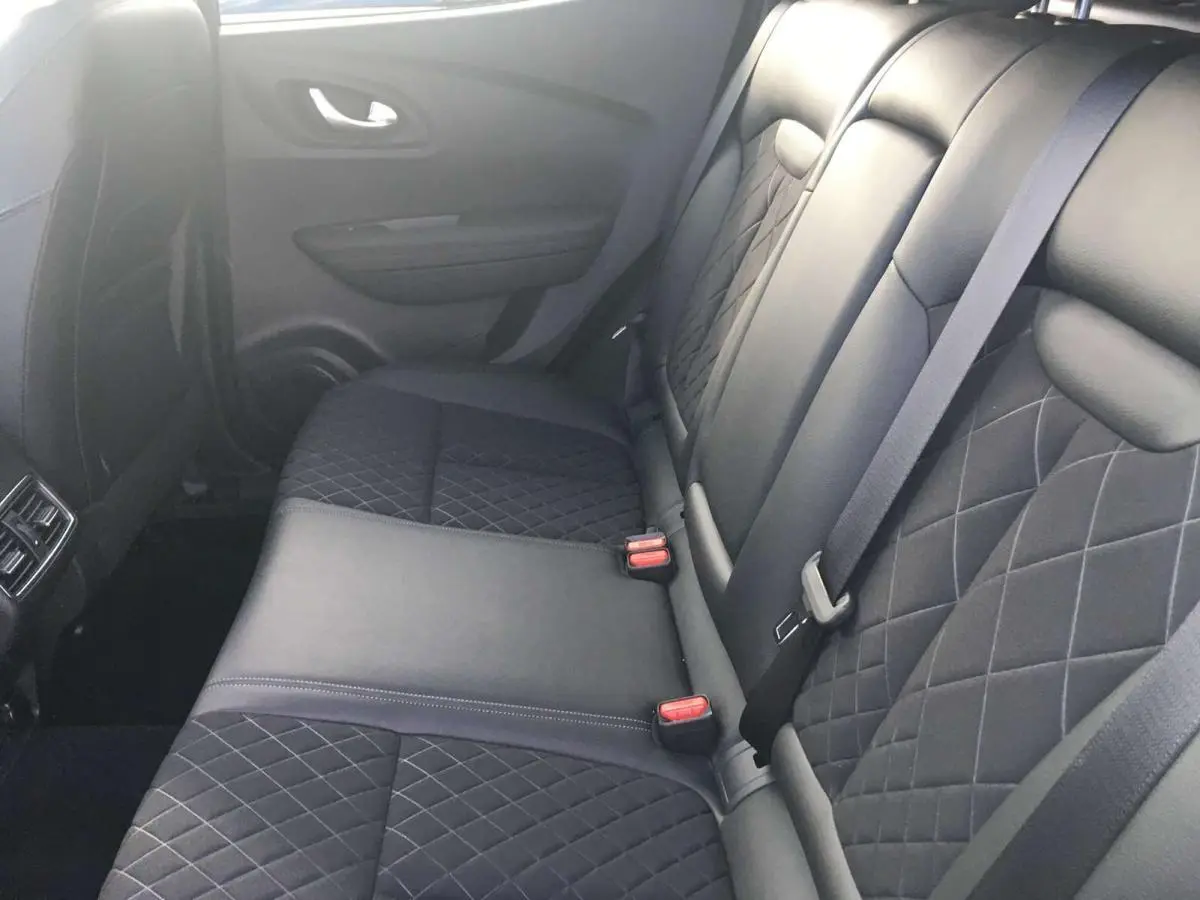 Vue latérale intérieure montrant la banquette arrière en cuir noir matelassé du Renault Kadjar gris titanium.