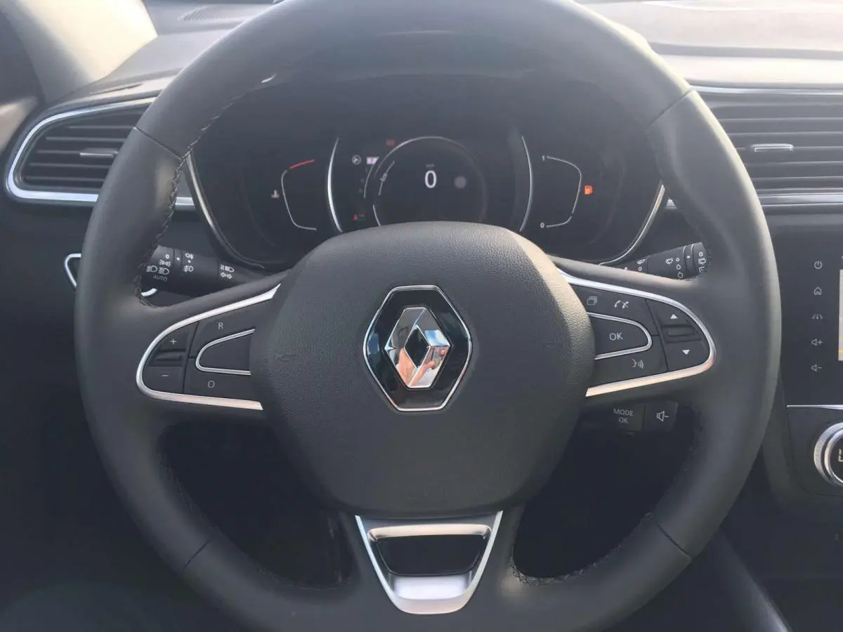 Vue rapprochée du volant noir de la Renault Kadjar 2020 avec logo central et commandes intégrées.