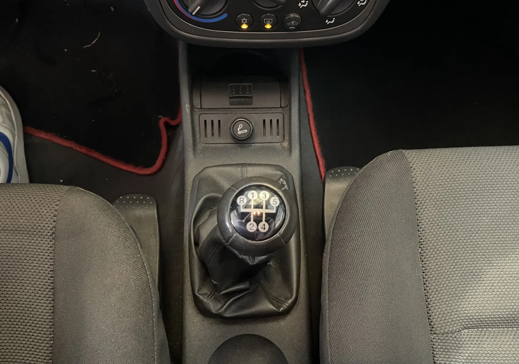 Vue rapprochée du levier de vitesses manuel noir entre les sièges avant gris foncé d'une Opel Tigra Twintop 2006.