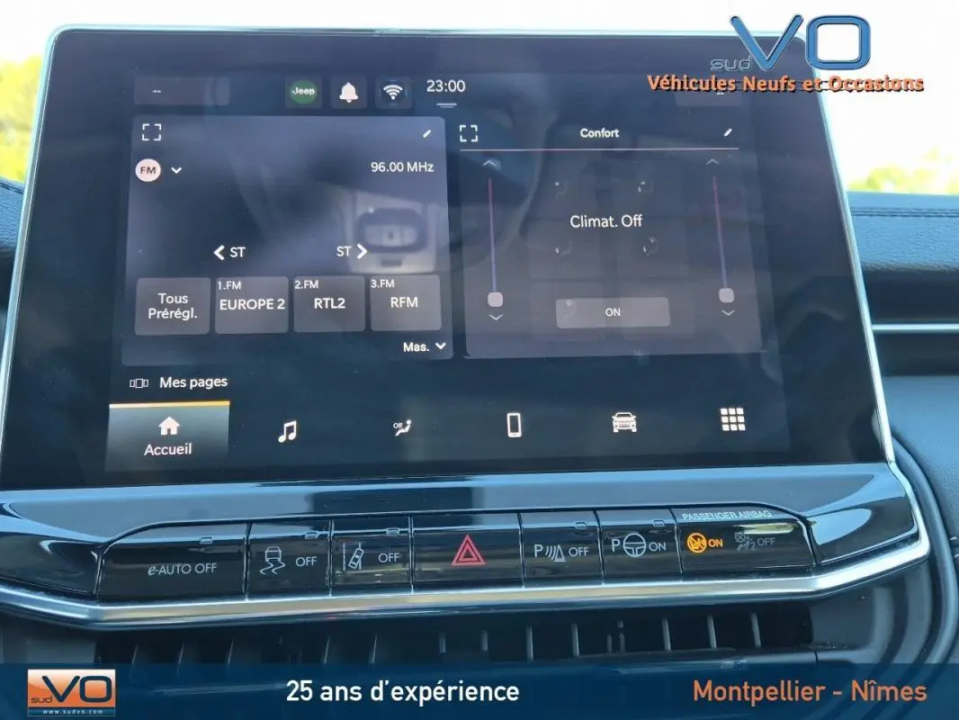 Écran tactile central du Jeep Compass 2024 gris montrant les réglages radio et climatisation, avec boutons de commande en dessous.