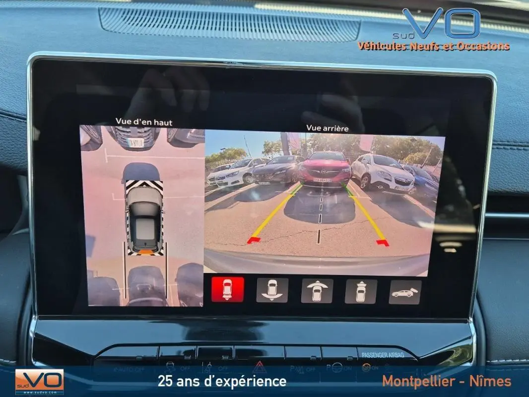 Écran tactile montrant la caméra de recul et vue 3/4 arrière du Jeep Compass gris 2024 avec aides au stationnement.